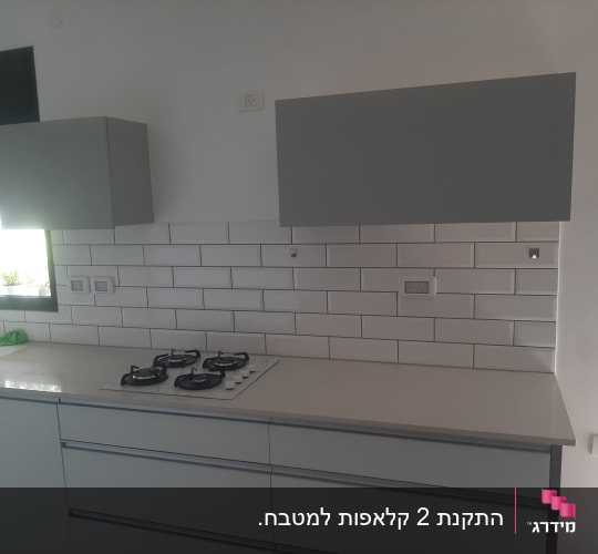 מטבח מודרני עם כיריים גז וארונות אפורים